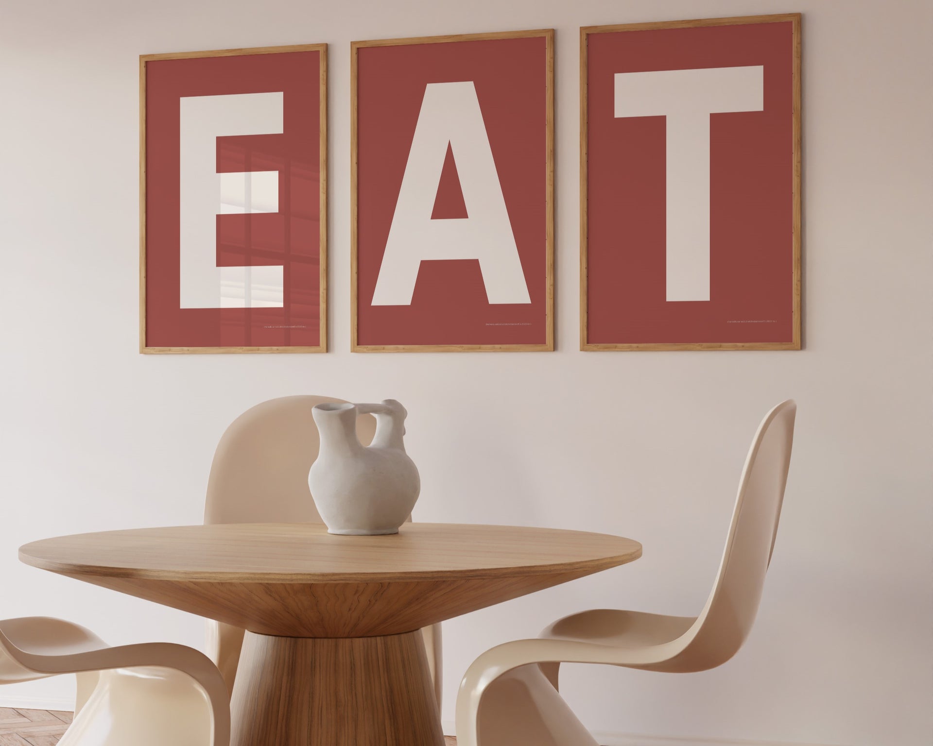 Three framed Nantucket red and white letter art prints spelling out the word EAT hanging in a modern dining room.