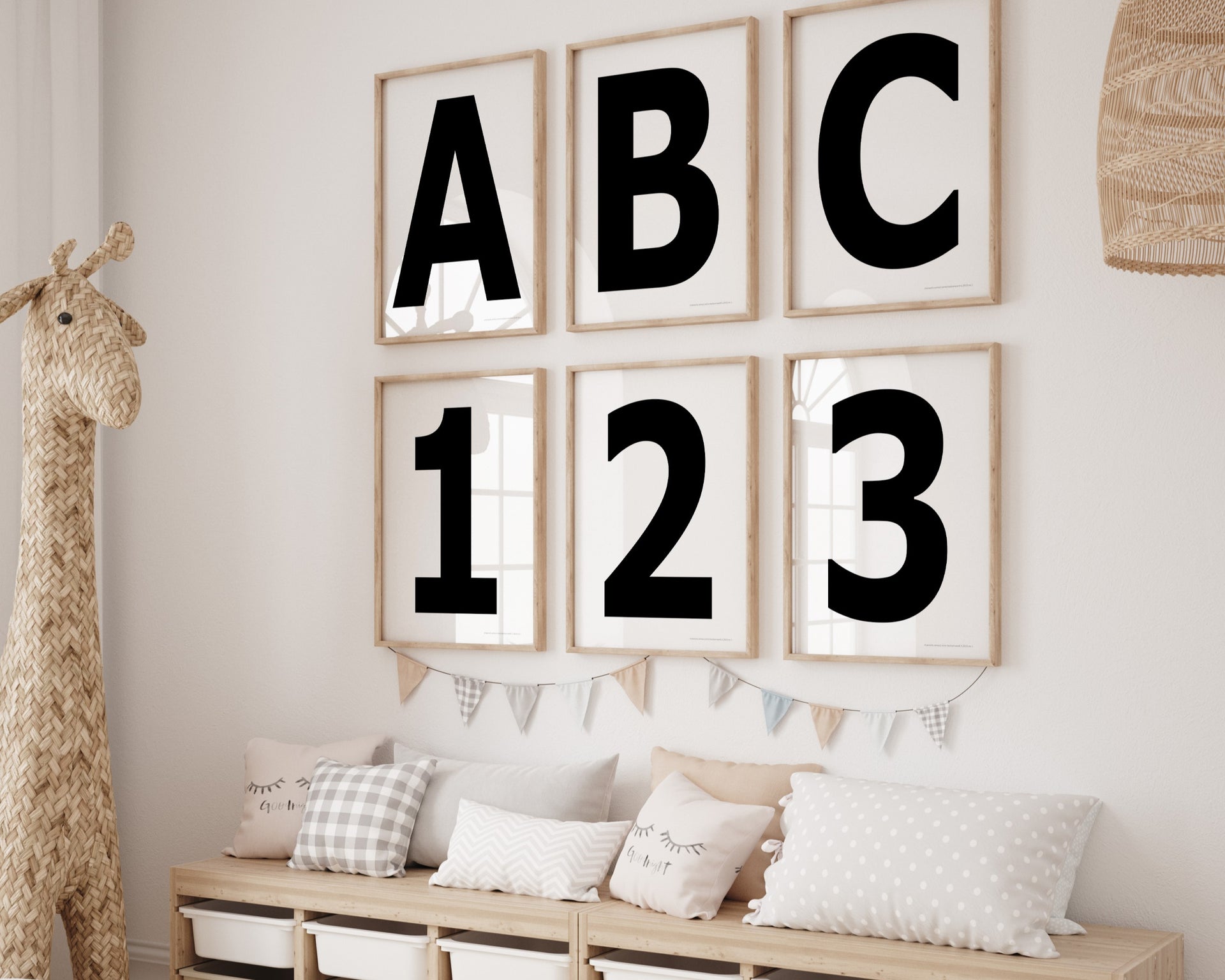 Six framed black and white letter and number art prints spelling out ABC123 hanging on a wall in a nursery or playroom.