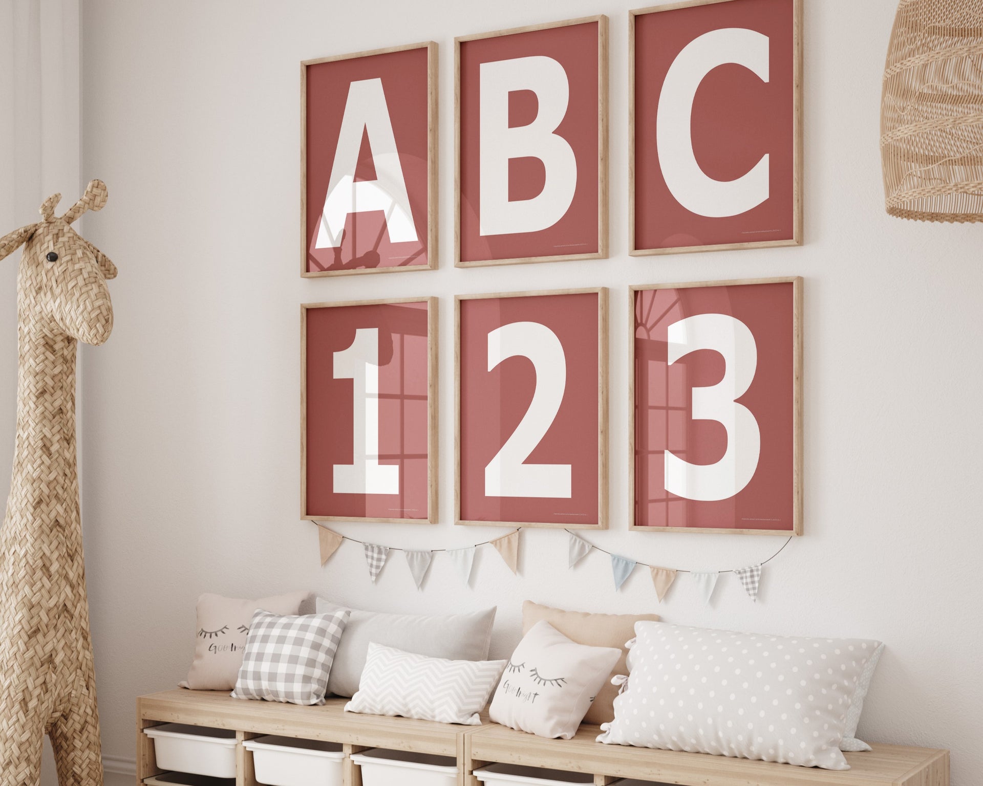 Six framed Nantucket red and white letter and number art prints spelling out ABC123 hanging on a wall in a nursery or playroom.