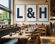 Three oversized framed navy blue and white letter and ampersand art prints spelling out the name of a restaurant hanging on the wall.