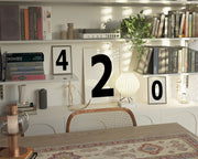 Three black and white framed number art prints spelling out 420 on an eclectic and modern bookshelf.