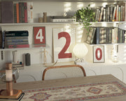 Three Nantucket red and white framed number art prints spelling out 420 on an eclectic and modern bookshelf.