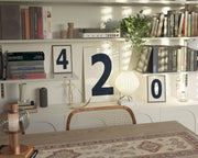 Three navy blue and white framed number art prints spelling out 420 on an eclectic and modern bookshelf.