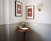 Two framed plus and minus art prints in a bathroom with green tile.