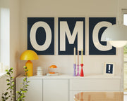 Three framed navy blue and white letter art prints spelling out OMG hanging above a credenza