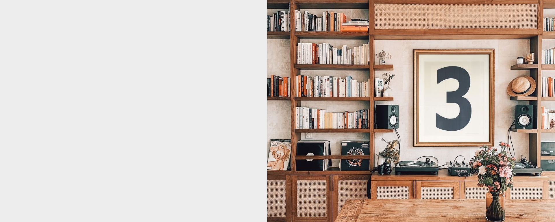 Large framed white and navy blue number three art print hanging above a mid century credenza in between bookshelves creating a modern library.