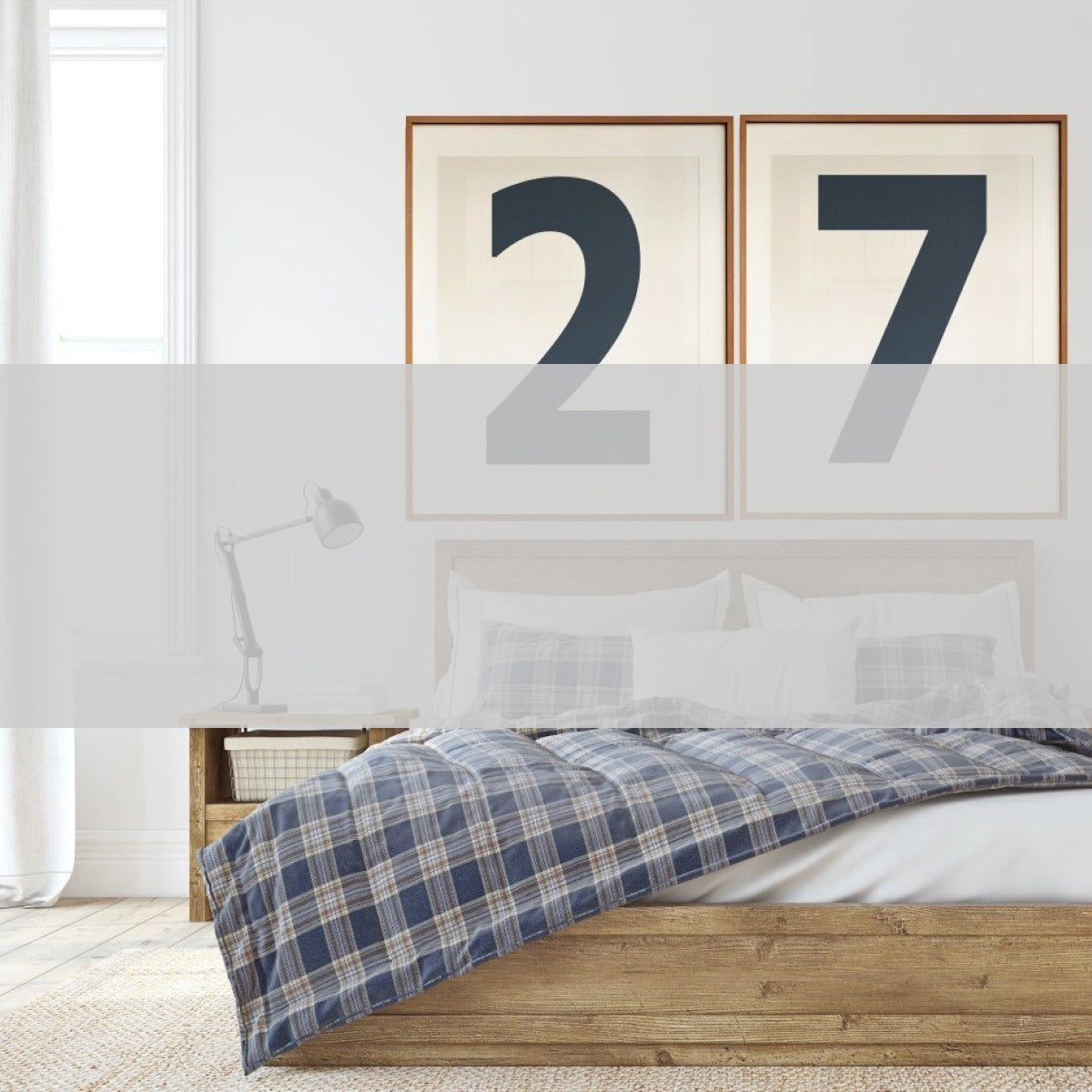 2 large framed white and navy blue number art prints showcasing a boy's jersey number 27 hanging above a bed with a plaid blanket.