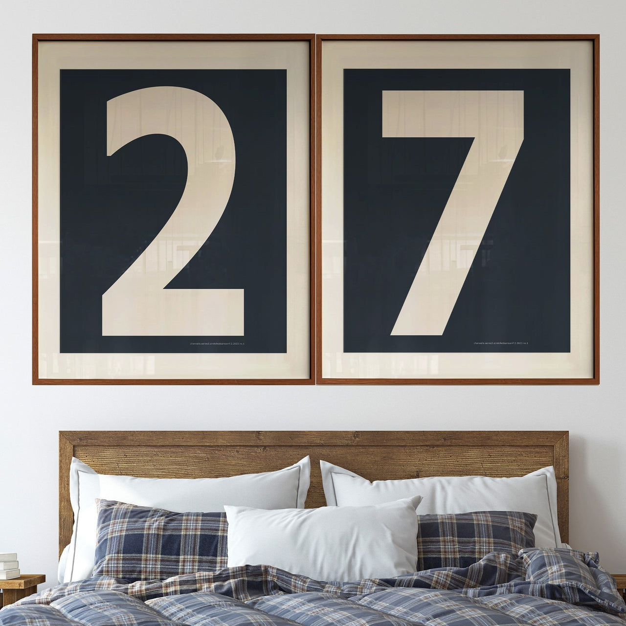 Two large framed navy blue and white number art prints showcasing a boy's jersey number 27 hanging above bed with plaid blanked.