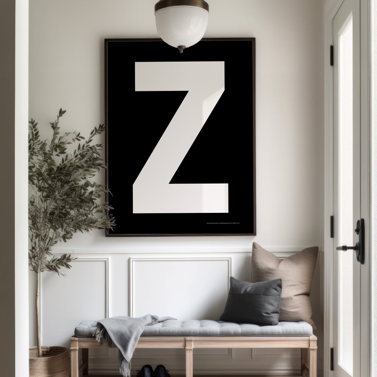 Oversized framed black and white letter Z art print hanging above a bench in a farmhouse entryway.